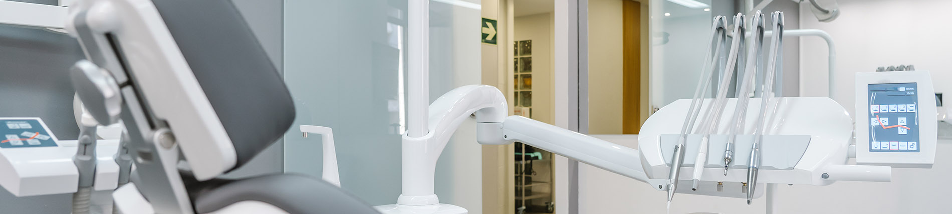 The image shows a modern dental clinic interior with various pieces of equipment, including a dental chair and an X-ray machine.
