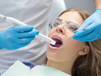 A woman receiving dental care with a dentist using a device to clean her teeth.
